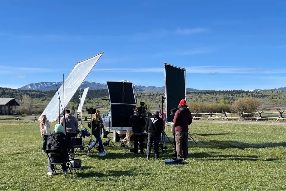 Film crew on an outdoor ranch shoot below snowy mountains